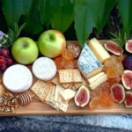 A cheese and fruit platter featuring an assortment of cheeses, fresh fruits like grapes and berries, nuts, and crackers, arranged on a wooden board.